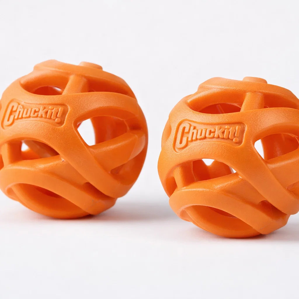 Two orange Chuckit Air Fetch Balls with open design on a white background
