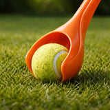 Orange tennis ball retriever with a tennis ball on grass