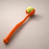 Orange spoon with a tennis ball on a beige background